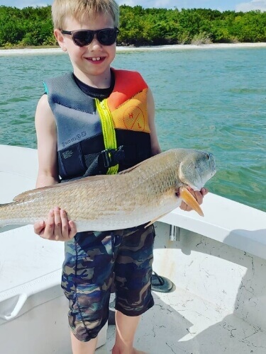 Child on a boat holding a fish that was caught in Tampa Bay