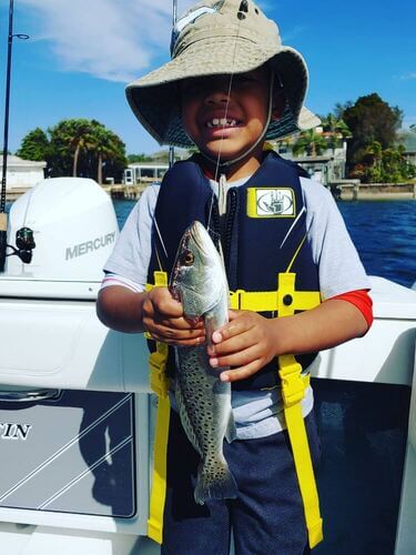 Child on a boat holding a fish they caught in Tampa Bay
