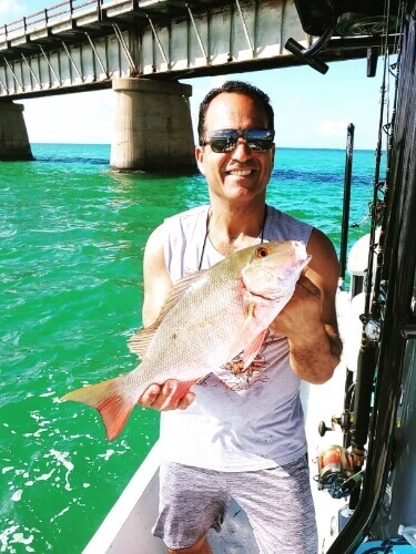 Gentleman on a boat holding a fish that was caught in Tampa Bay