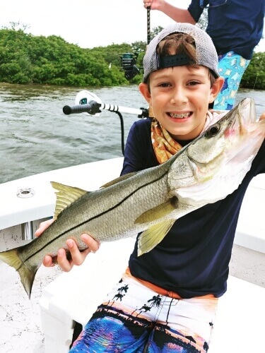 Child on a boat holding a fish they caught